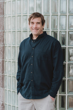 A picture of Phil House, il porcellino salumi's wholesale manager, in front of windows at their wholesale facility in Basalt.