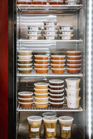 il porcellino salumi's deli refrigerator case with a different sauces, pickled vegetables, peanut butter and other house-made condiments.