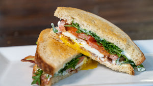 il porcellino salumi's Breakfast BLT Sandwich on a plate with one half of the sandwich stacked on the other half for display.