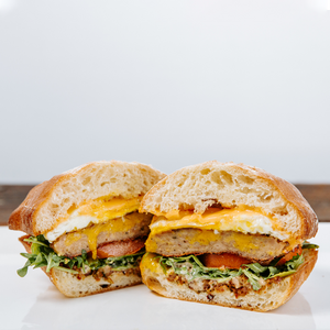 Two halves of il porcellino salumi's Breakfast Burger sandwich on a plat and facing the camera to show the ingredients.