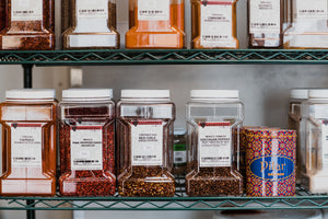 Two shelves filled with large bins of premium herbs and spices.