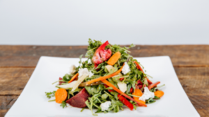 il porcellino salumi's Root Vegetable Salad displayed on a plate which is on a wood table.