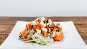 il porcellino salumi's The Wedge salad displayed on a plate which is on a wood table.