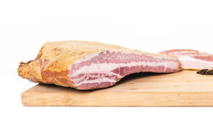 The cross section of a bacon slab on a cutting board to show the fat to meat ratio.