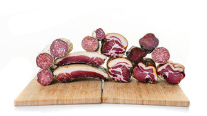 A bunch of cured meats stacked on top of each other on cutting boards and displayed to show their cross sections.
