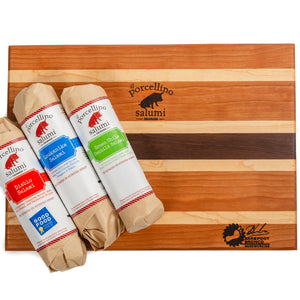 A product photo of a cutting board branded with the il porcellino salumi and barefoot bronco logos and with three wrapped salami flavors on it.