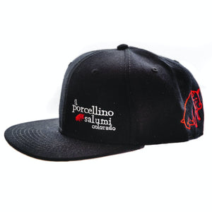 A black baseball hat pictured at the side with il porcellino salumi's name on the front left and the brands logo on the back left of the hat.