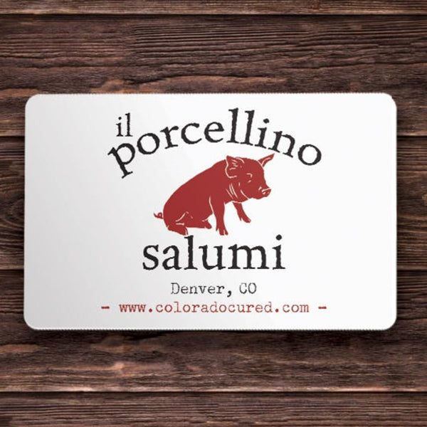 A picture of a gift card with the words "il porcellino salumi, Denver, CO" on it with a wood grain background.